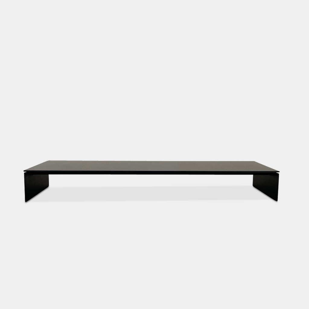 The Porro Modern Light Low Table by Piero Lissoni showcases a minimalist black design with a sleek metal structure and simple, rectangular legs, set against a plain background.