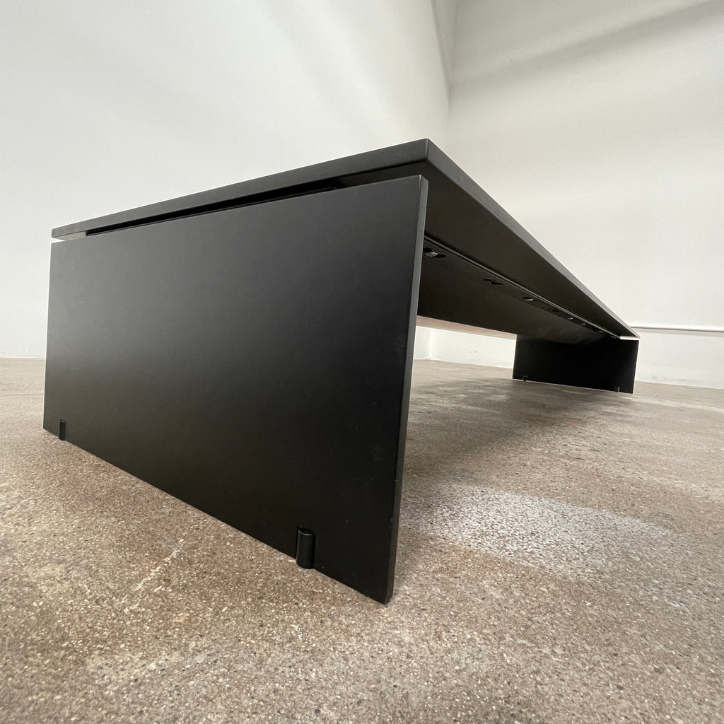 The Porro Modern Light Low Table by Piero Lissoni showcases a minimalist black design with a sleek metal structure and simple, rectangular legs, set against a plain background.