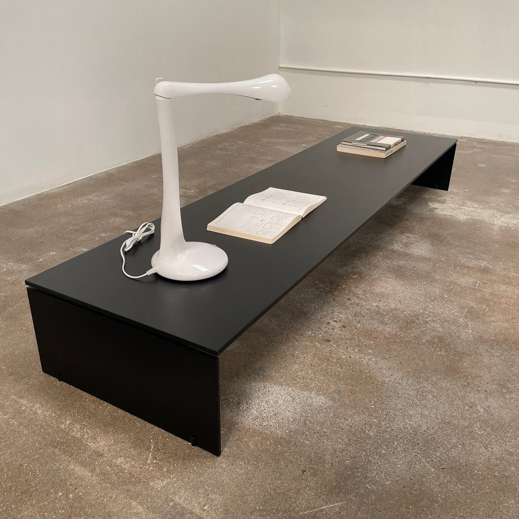 The Porro Modern Light Low Table by Piero Lissoni showcases a minimalist black design with a sleek metal structure and simple, rectangular legs, set against a plain background.