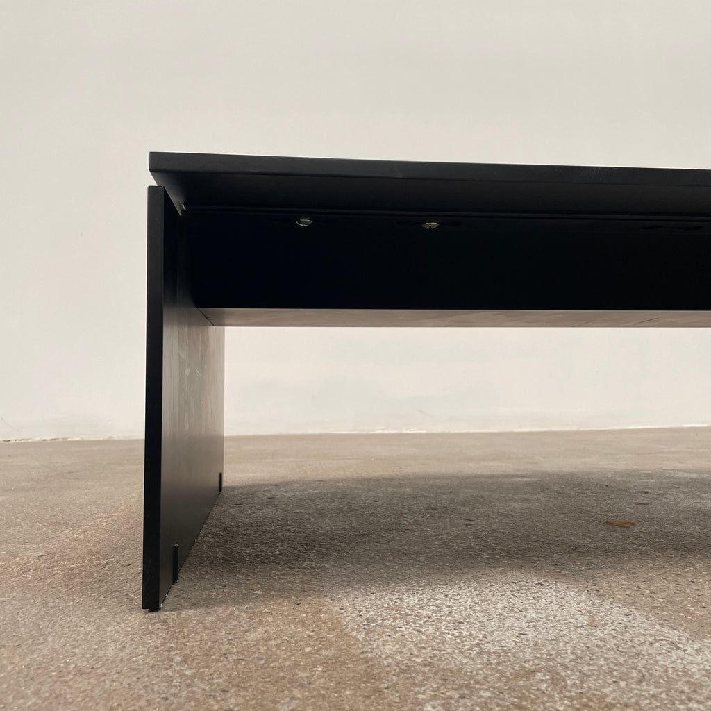 The Porro Modern Light Low Table by Piero Lissoni showcases a minimalist black design with a sleek metal structure and simple, rectangular legs, set against a plain background.