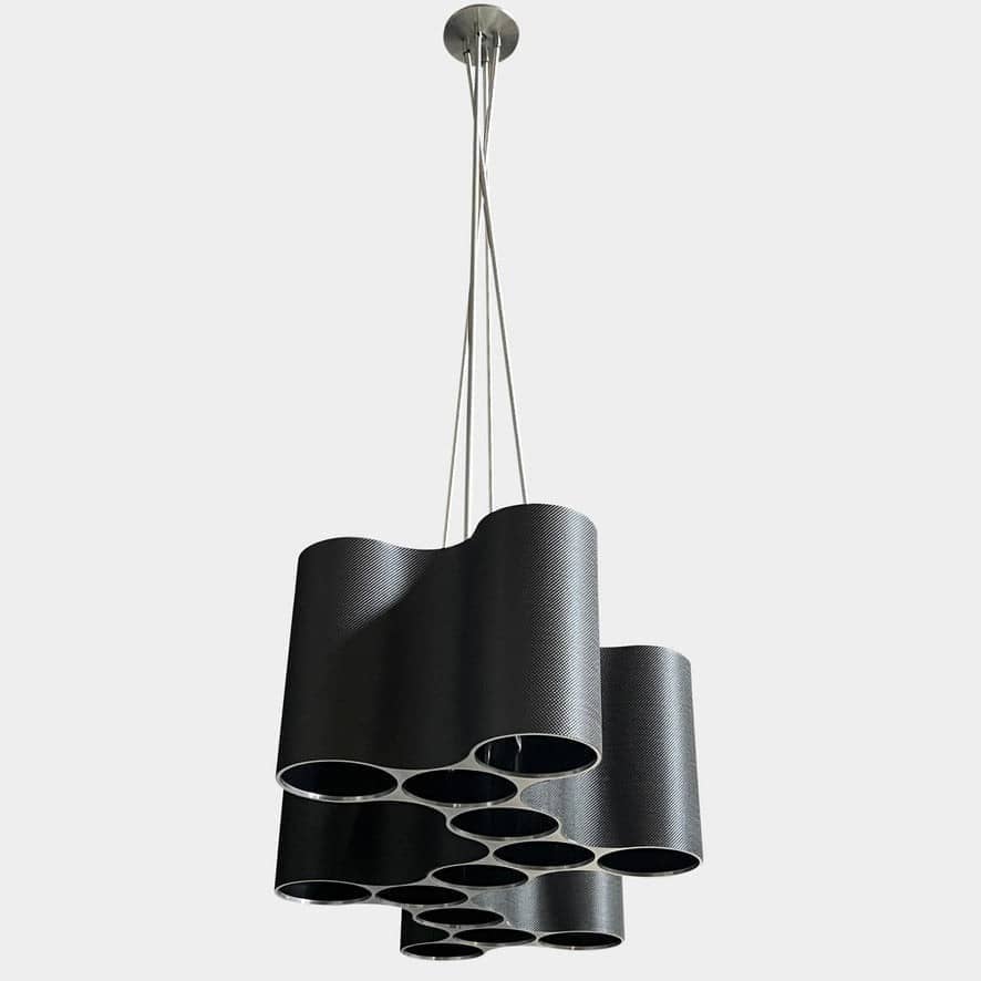 A modern metal chandelier with multiple cylindrical shades connected by thin, curved attachments, hanging from a ceiling mount—a design reminiscent of the Ralph Pucci Linear Cumulus Ceiling Light.