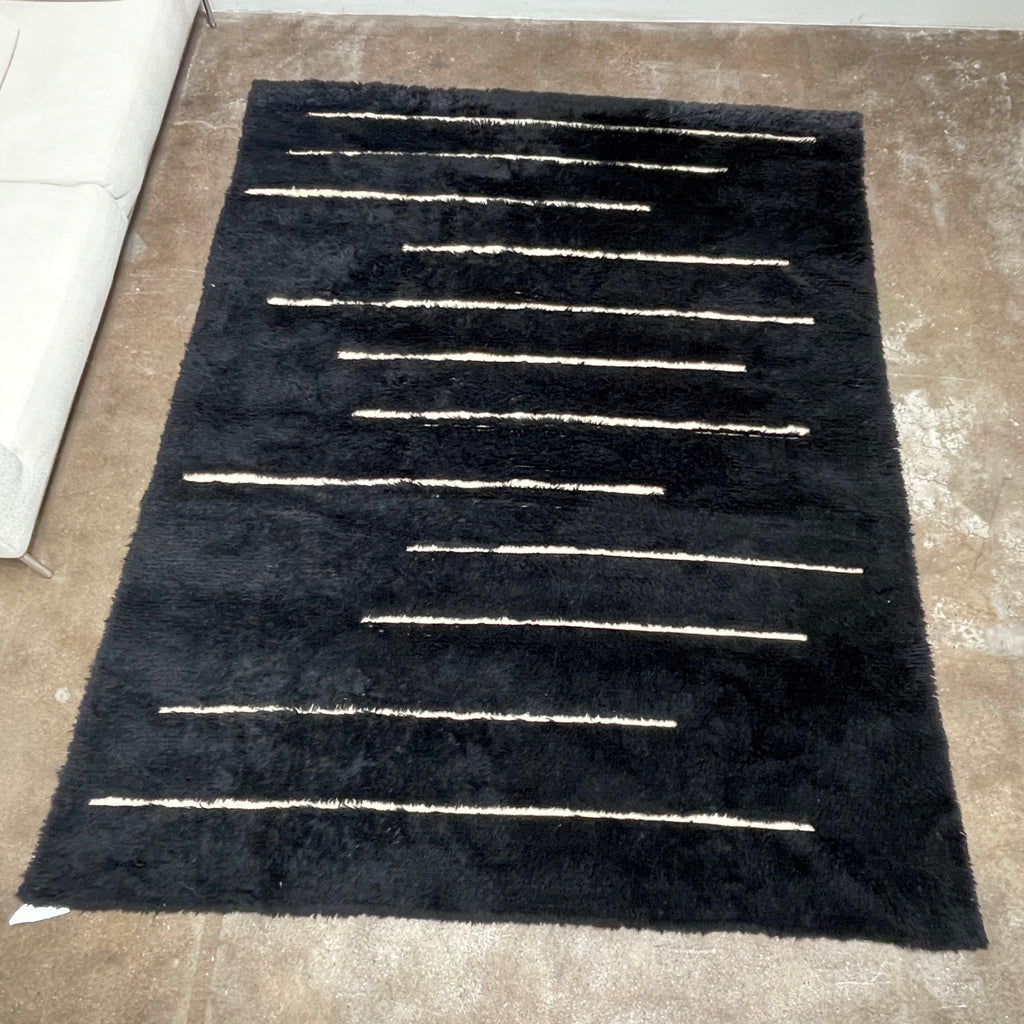 Close-up of a Woven Dilla Black & Ivory wool rug with diagonal white stitching, creating a distinct pattern on a high/low pile surface.