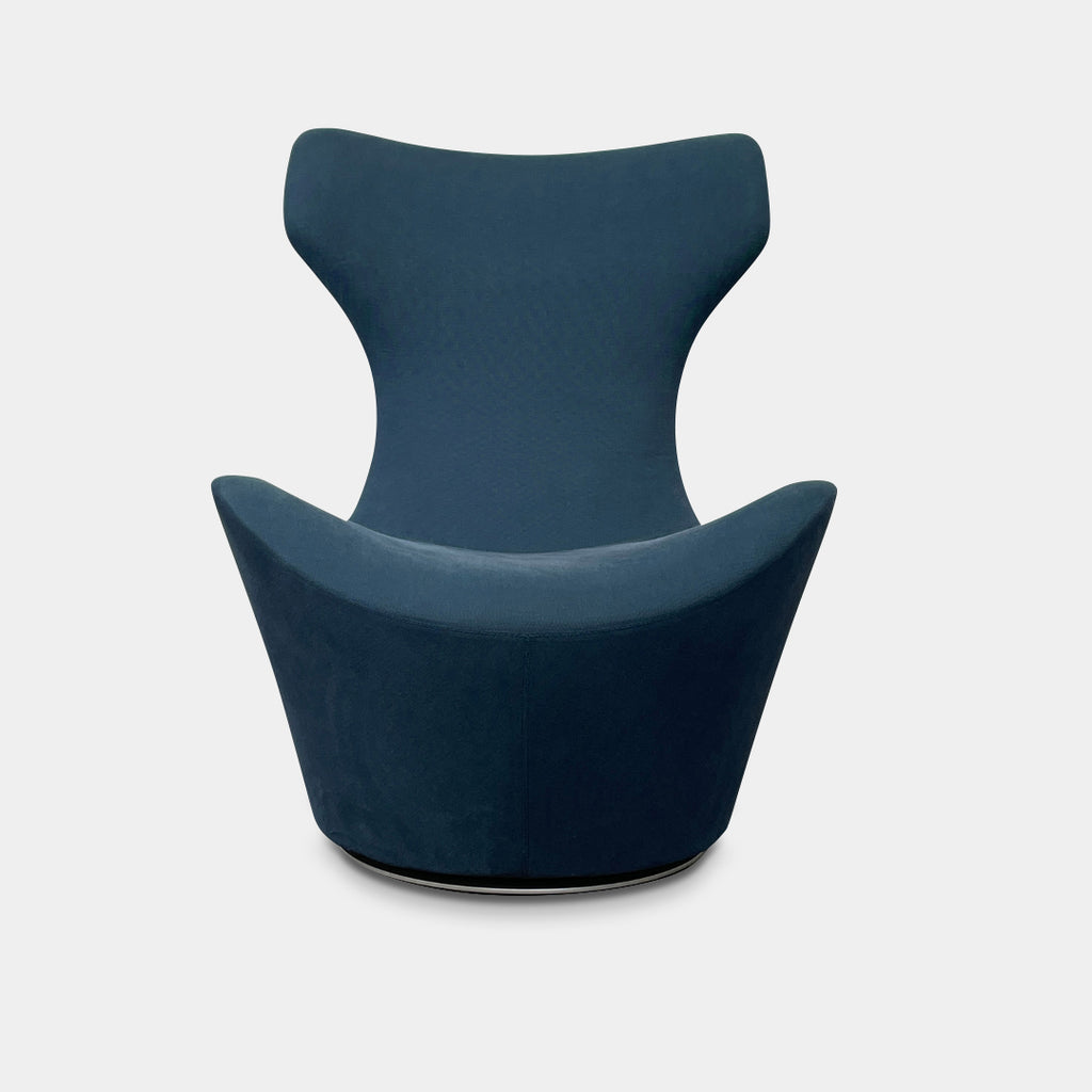 A modern, dark blue B&B Italia Grande Papilio Swivel Chair by Naoto Fukasawa showcases a curved design with a high backrest and wide seat, set against a plain white background.