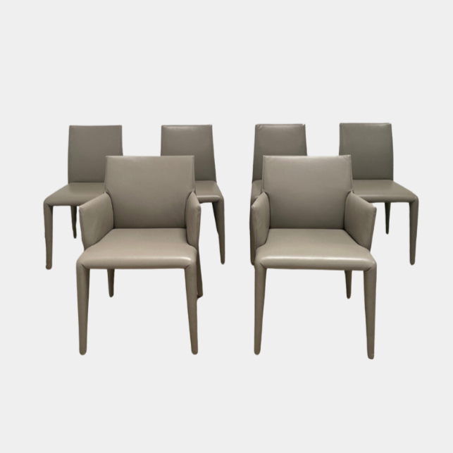 Six B&B Italia Vol au Vent Dining Chairs, embodying the elegance of Italian style, are arranged in two rows in an empty room with a concrete floor and a plain white wall.